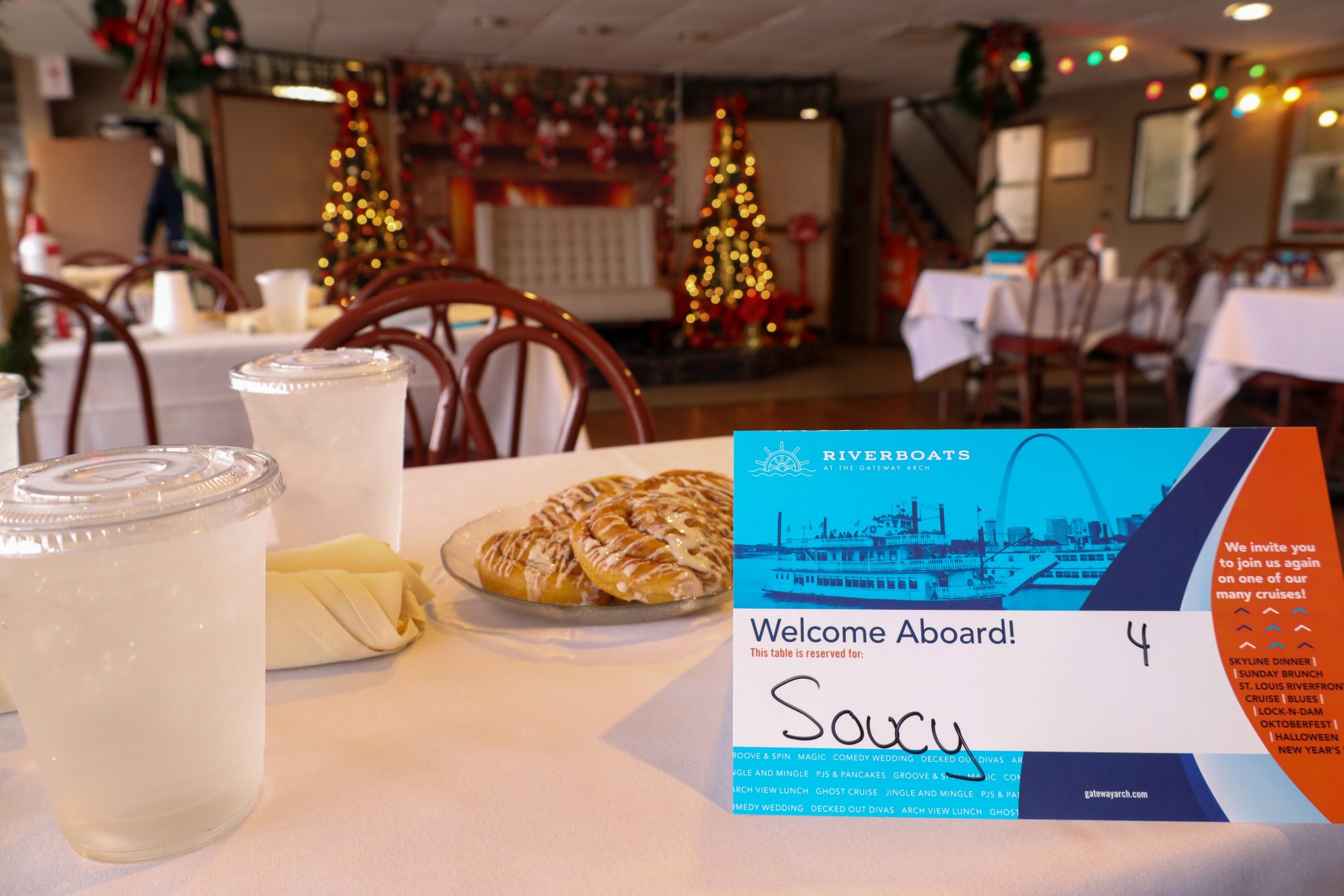 A placemat is set on a table with drinks, silverware and cinnamon rolls before a cruise on the Riverboats at the Gateway Arch.