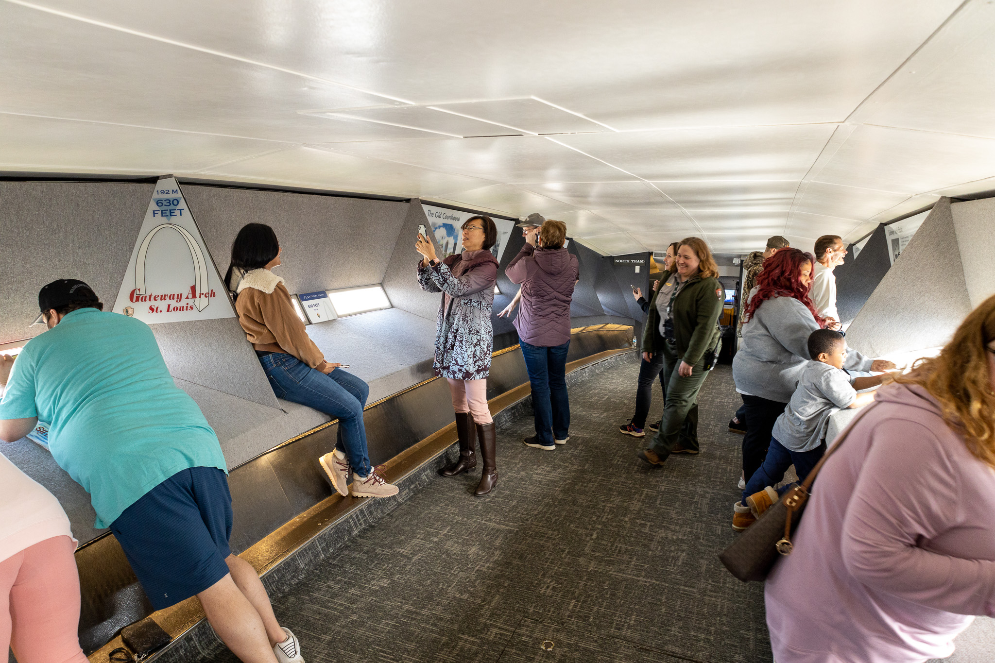 Dozens of guests are taking photos and looking out the windows at the top of the Gateway Arch.