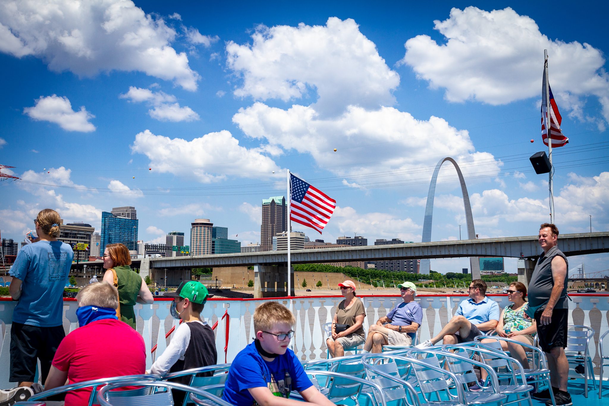 Guests on the top deck of the Tom Sawyer riverboat soak in the beautiful views of St. Louis with the Gateway Arch in the background.