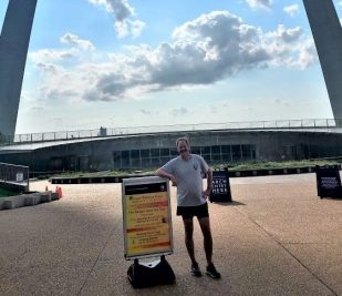 Ranger Frank of Gateway Arch National Park standing in front of the Arch one morning before beginning his running tour.